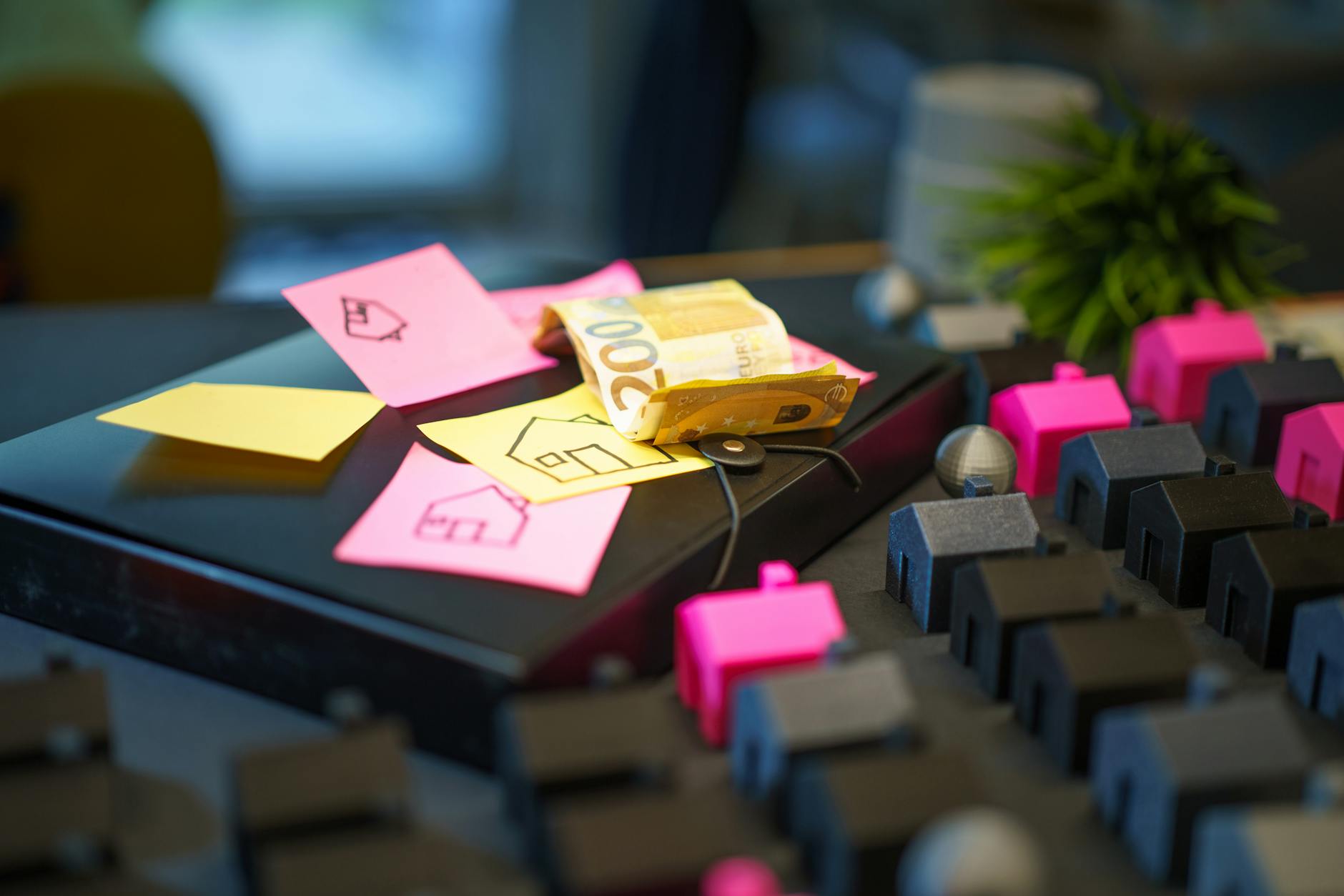 Ile kosztuje ubezpieczenie Geely i co realnie podnosi składkę? Banknoty euro na laptopie obok karteczek i małych domków