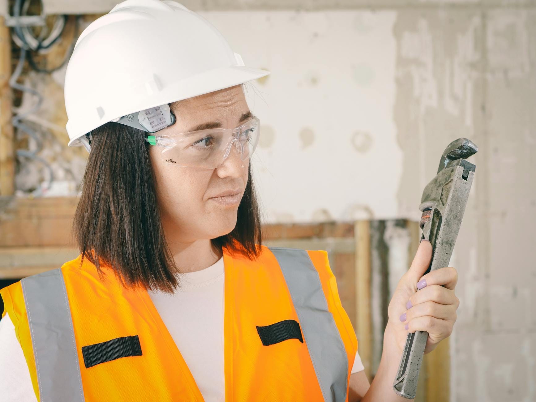 Kobieta w odzieży ochronnej trzyma klucz hydrauliczny podczas naprawy