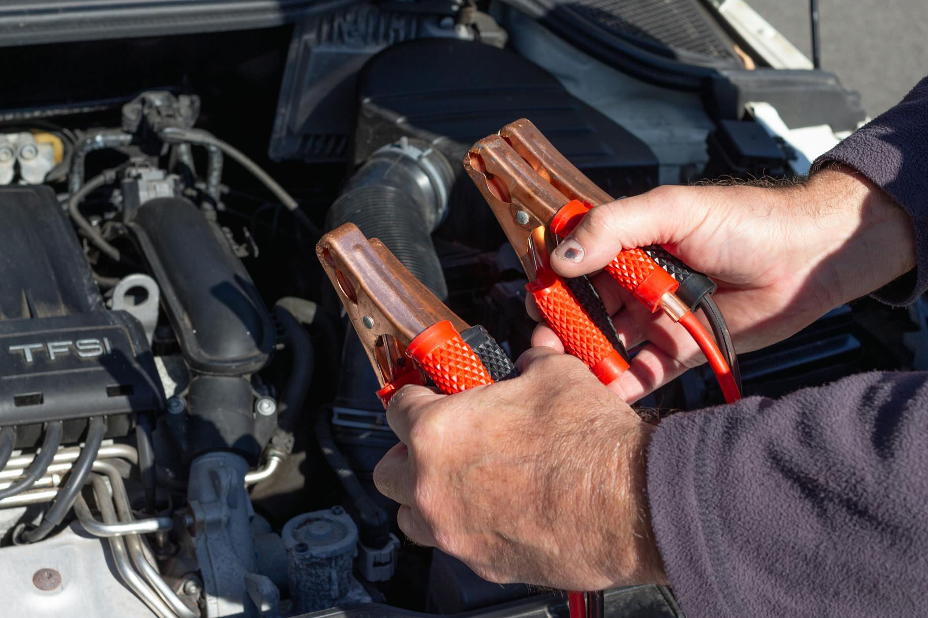 Mechanik trzyma kable rozruchowe przy silniku Tesli