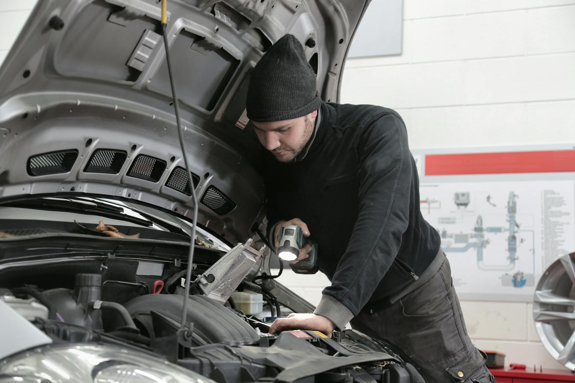 Mechanik z latarką ogląda silnik Volvo w warsztacie