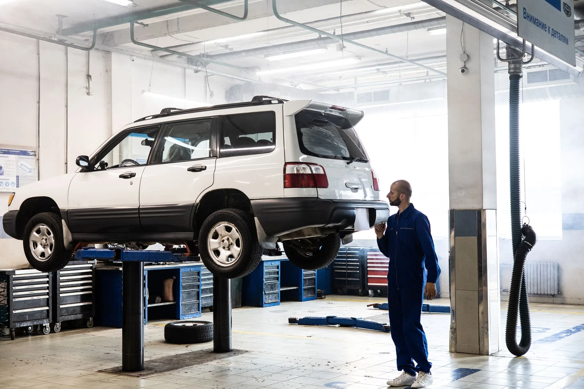 Mechanik sprawdza zawieszonego SUV-a w nowoczesnym warsztacie Mechanik sprawdza zawieszonego SUV-a w nowoczesnym warsztacie