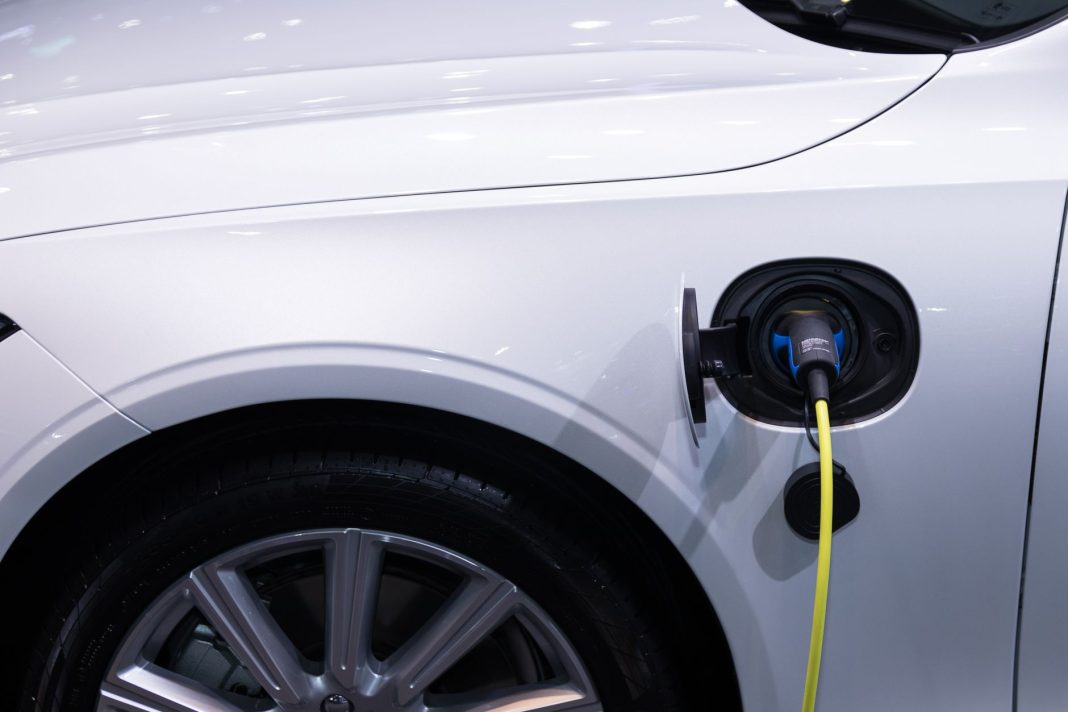 Białe auto elektryczne podłączone do ładowania, zbliżenie gniazda Białe auto elektryczne podłączone do ładowania, zbliżenie gniazda