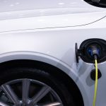 BYD kontra Toyota: czy hybrydy DM i mają sens poza miastem? Białe auto elektryczne podłączone do ładowania, zbliżenie gniazda