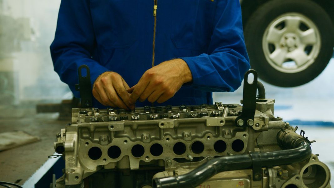 Mechanik naprawiający silnik Chevroleta Cruze w warsztacie Mechanik naprawiający silnik Chevroleta Cruze w warsztacie
