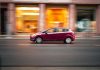 Ford Focus czy Fiesta na miasto: co wybrać? Czerwony miejski Ford jedzie szybko po ulicy na tle rozmytego miasta